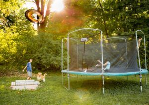 Barn som leker i trädgården och hoppar på en studsmatta för barn